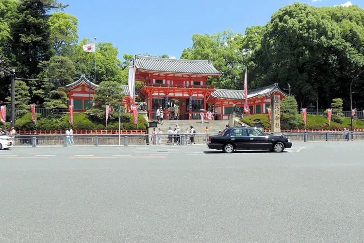京都・八坂神社前を走るタクシーと神社の門