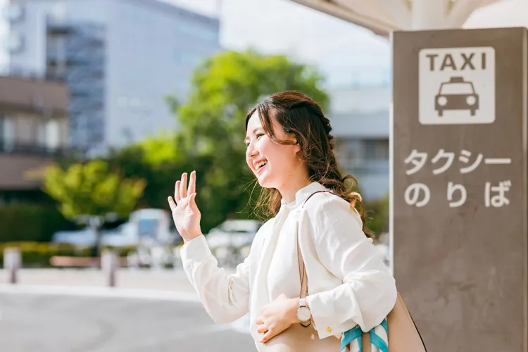 手を上げてタクシーを停める女性