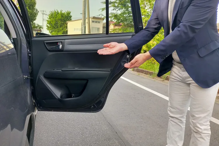 ドアを開けてエスコートするタクシードライバー