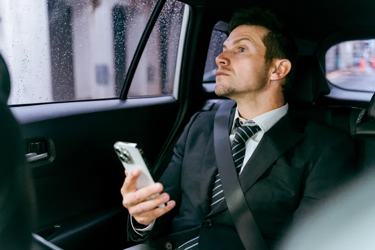 タクシーの車内でスマートフォンを操作するビジネスマン