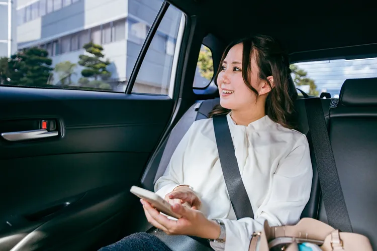 タクシーの車内でスマホを操作する女性