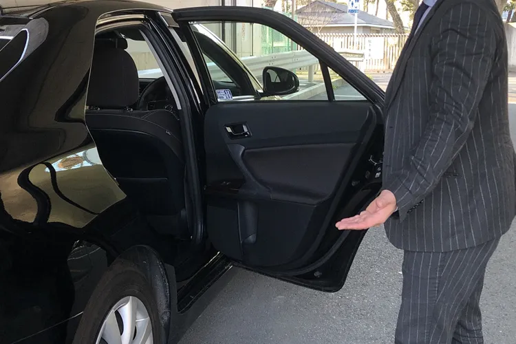 ハイヤーのドアを開ける運転手