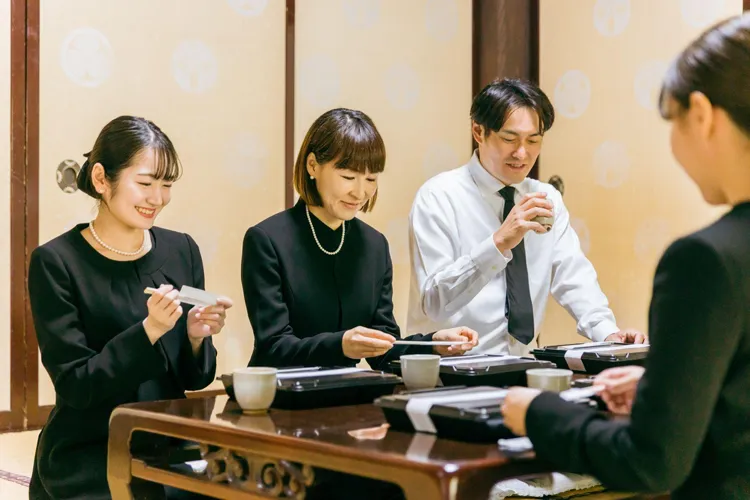 お斎で食事をとる参列者