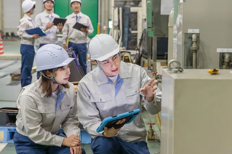 視察先で機械の説明を受ける女性社員