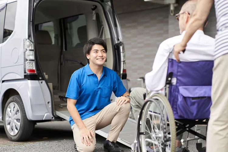 スロープタイプの福祉タクシーを利用する車いすの男性
