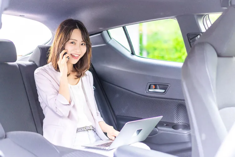 タクシーの車内で仕事をする女性