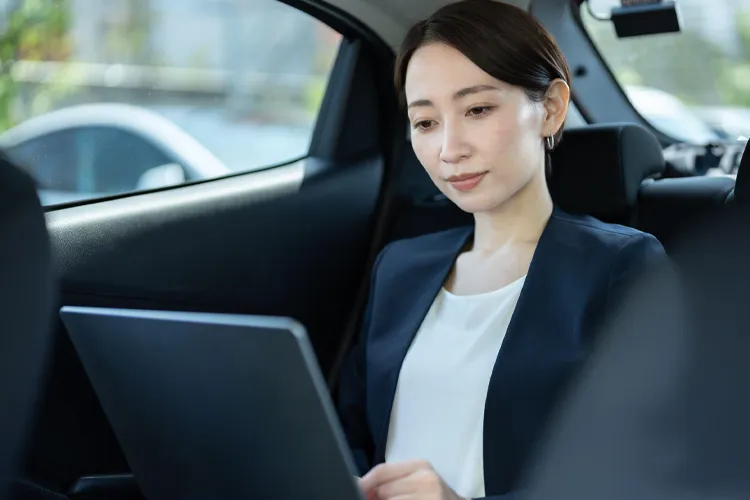 タクシーの車内でノートパソコンを開く女性
