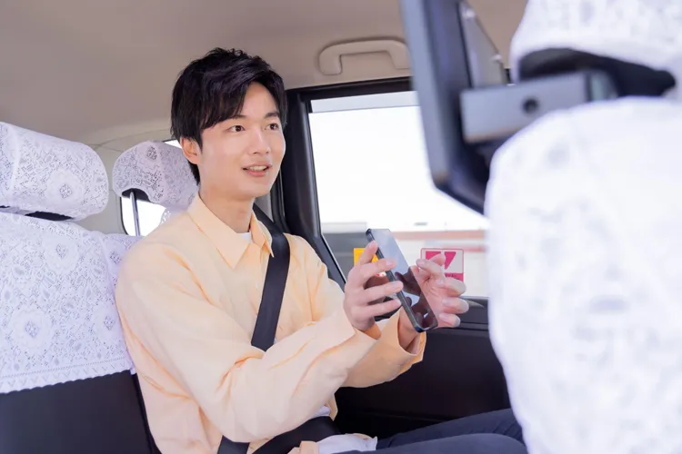 タクシーの車内でスマホを見せる男性